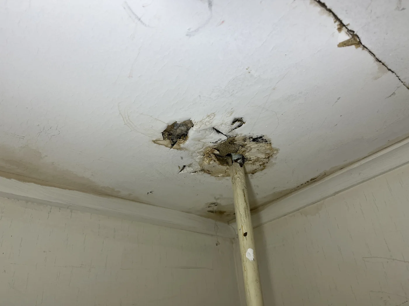 Ceiling staining and damage around a ceiling penetration or pipe area.