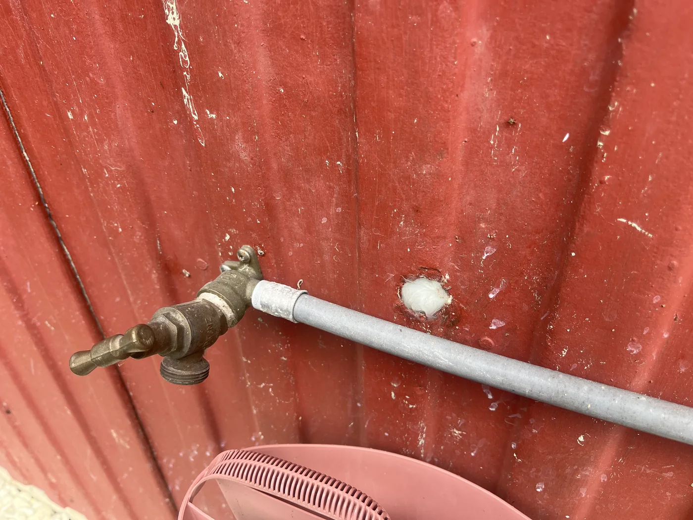 Service pipe penetration through exterior wall with visible sealing concerns.